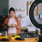 Perempuan memasak di dapur sambil merekam konten untuk jualan makanan online